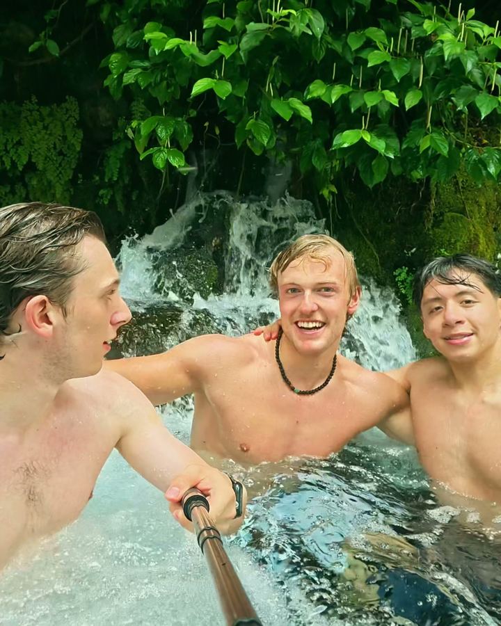 Drei Freunde baden unter einem Wasserfall